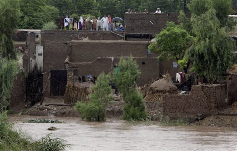 Pakistani stranded people stand on the rooftop of their houses at a flood hit village near Nowshera , Pakistan on Thursday, July 29, 2010. Rivers burst their banks during monsoon rains, washing away streets, battering a dam and killing at least 60 people in most severe floods in decades in northwest Pakistan, officials said Thursday.(AP Photo/Mohammad Sajjad)